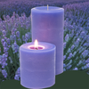 Two purple candles with a lit one in front of a lavender field
